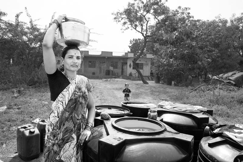 Carrying drinking water home from filled tanks stored along the roadside in a village in Ahmednagar district, Maharashtra